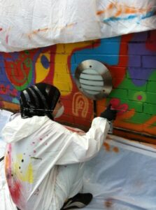 Girl seen from behind in protective clothing painting