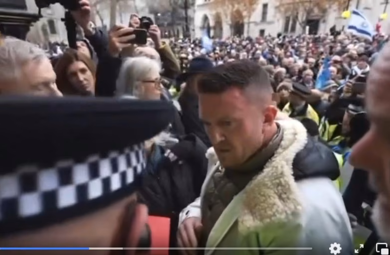 Man and police officer in front of large crowd