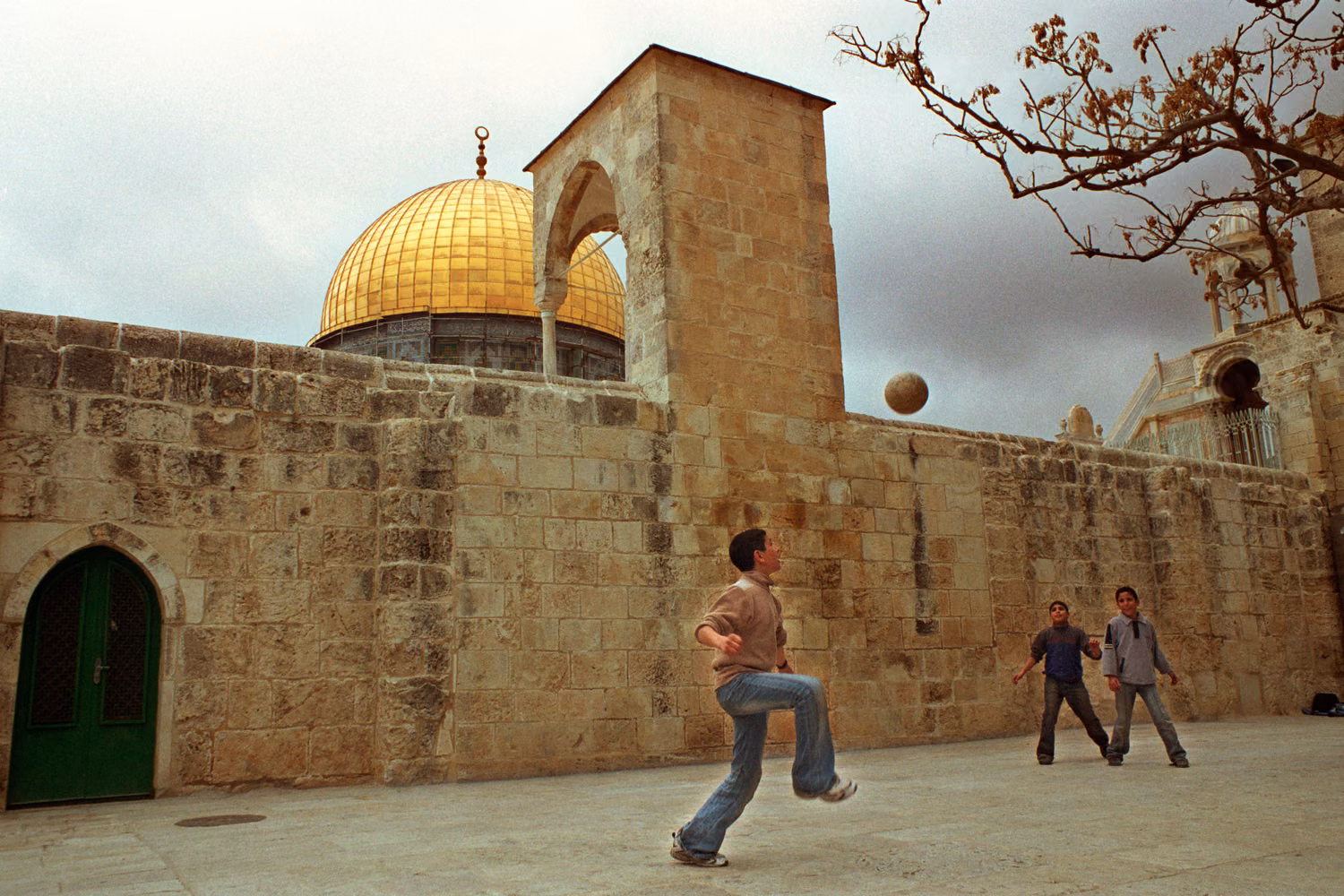 boys play football beside the East Jerusalem city wall