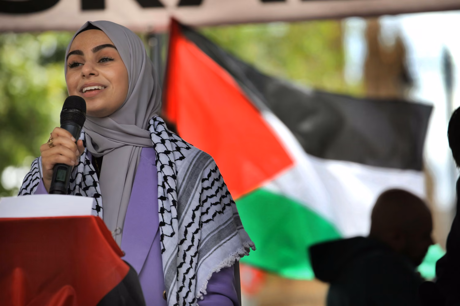 Young woman with microphone in front to flag