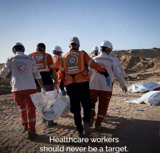 Men seen from behind carrying a corpse swathed in white.
