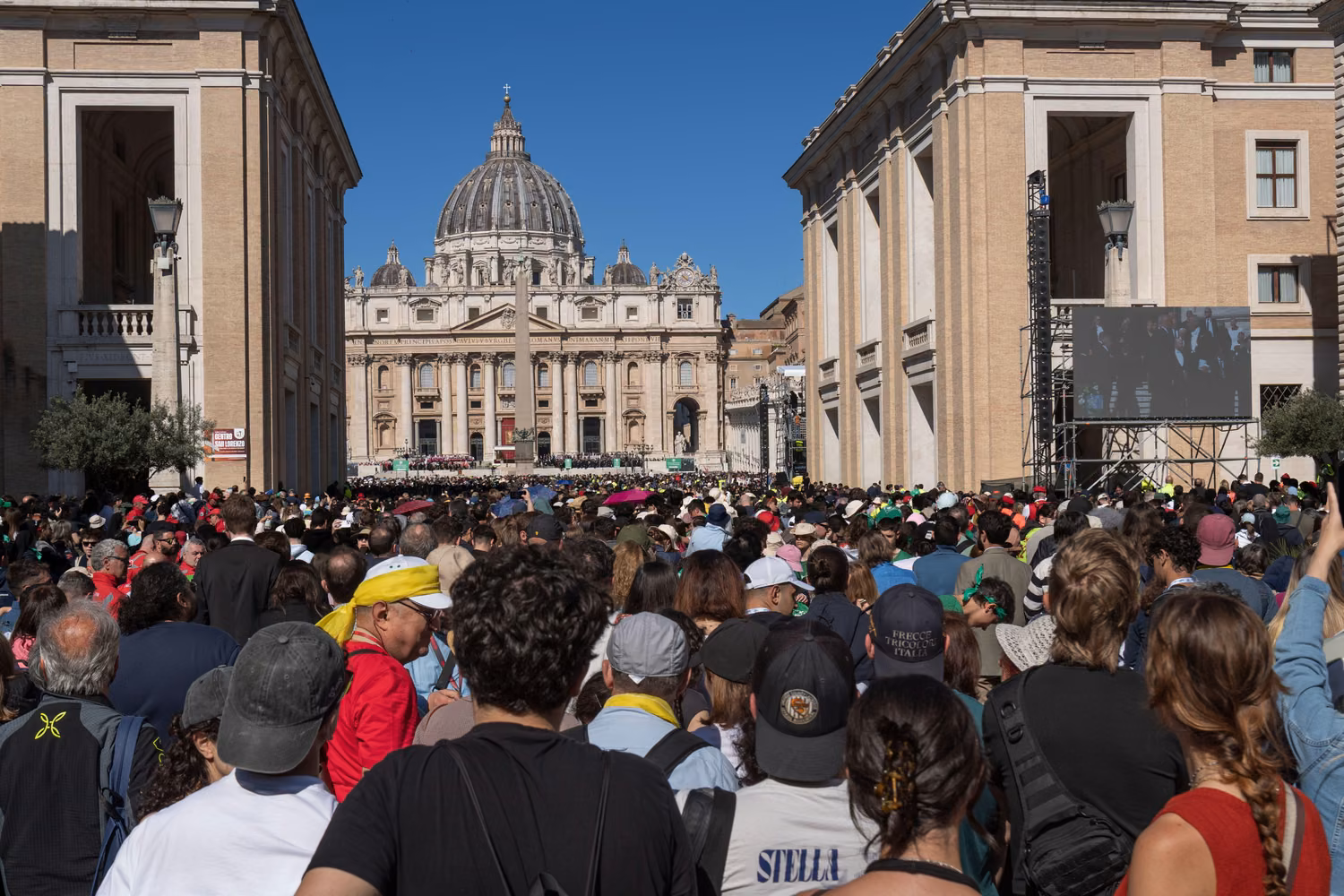 Crowds of people seen from behind facing a church