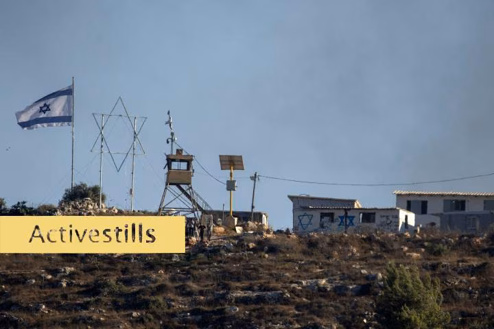 low buildings and lookout post on hilltop with flag flying
