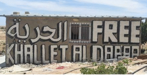 graffiti on a wall with writing in arabic and english; saying "Free Khalet a=Dabe