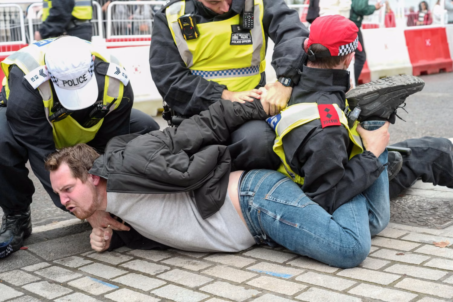 Police hold down a male protester on the ground