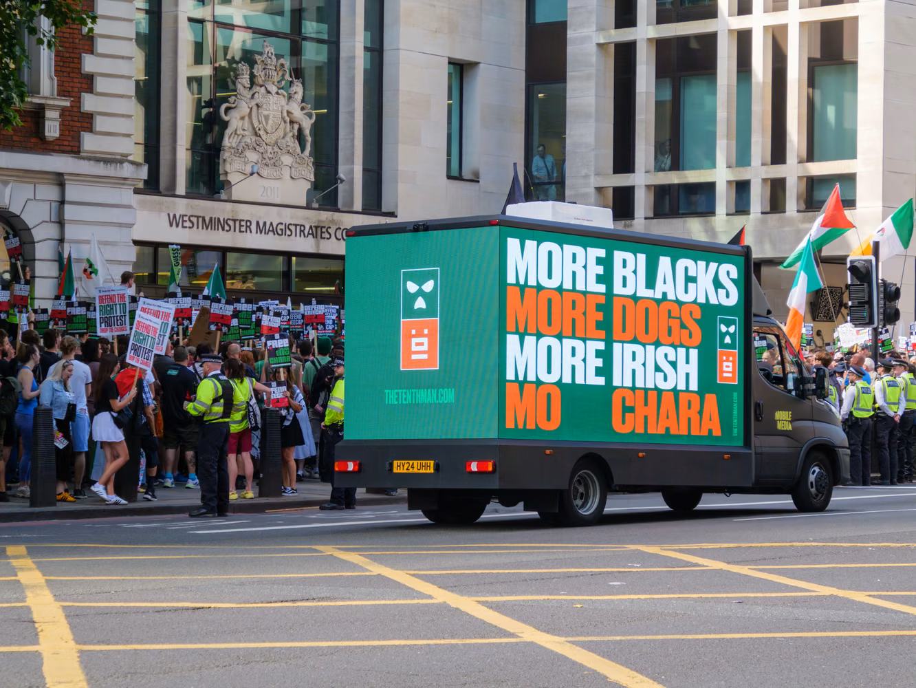 Lorry with politicial slogans in front of a crowd protesting outside a courthouse.