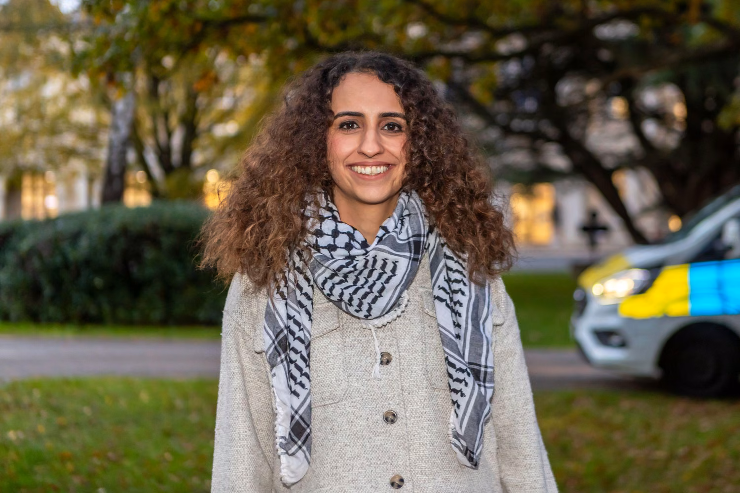 Young woman with long dark curly hair smiling
